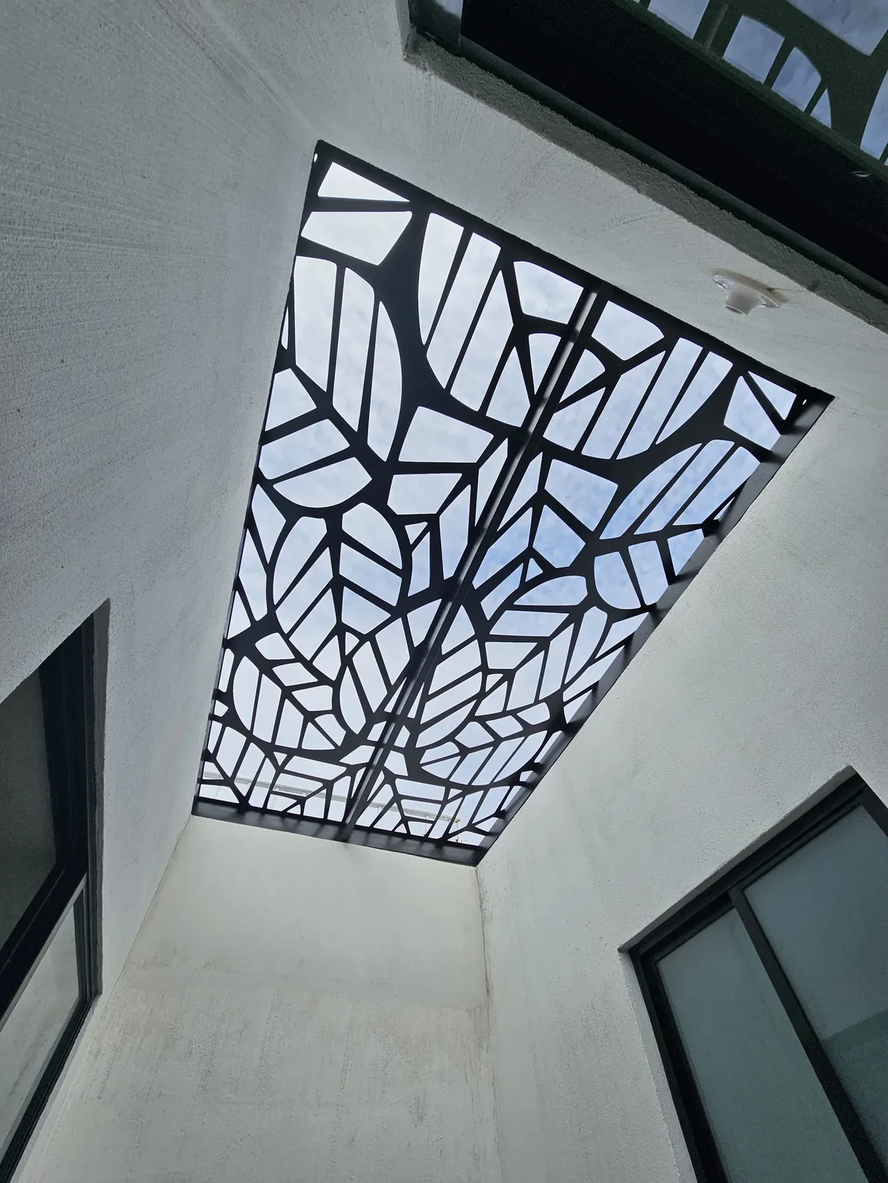 celosia metalica de techo con diseno de hojas en cubo de luz vista desde el interior
